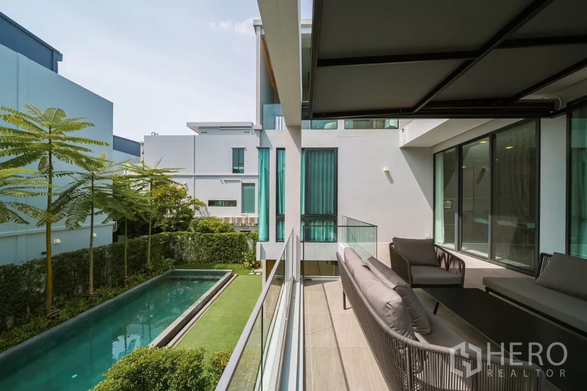 บ้าน ให้เช่าหรือขายในSaphan Sung, Bangkok - ระเบียงนั่งเล่นชมสระแบบสระยาว สนามหญ้า และบ้านสไตล์มินิมอลรอบข้าง