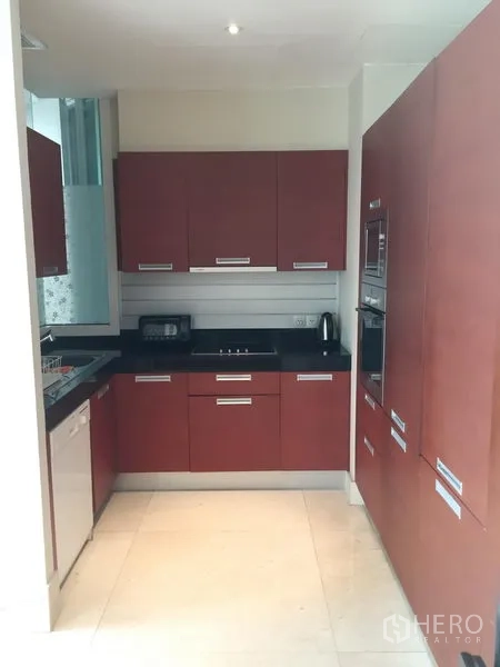 Condominium for rent or sale in Bang Rak, Bangkok - Modern U-shaped kitchen with wood cabinetry, black countertops, and built-in oven.