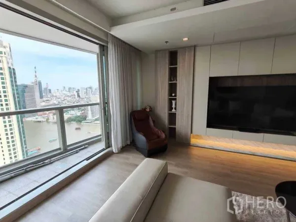 คอนโด ขายในKhlong San, Bangkok - มุมนั่งพักผ่อนข้างหน้าต่างพาโนรามา เห็นวิวแม่น้ำและสกายไลน์กรุงเทพฯ พร้อมชั้นวางบิวท์อิน