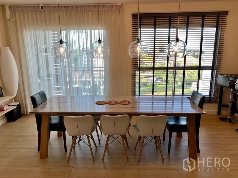คอนโด ให้เช่าในBang Na, Bangkok - ห้องทานอาหารรับแสงเต็มที่ หน้าต่างเต็มผนัง ม่านโปร่ง และโคมไฟสามดวงเหนือโต๊ะยาว