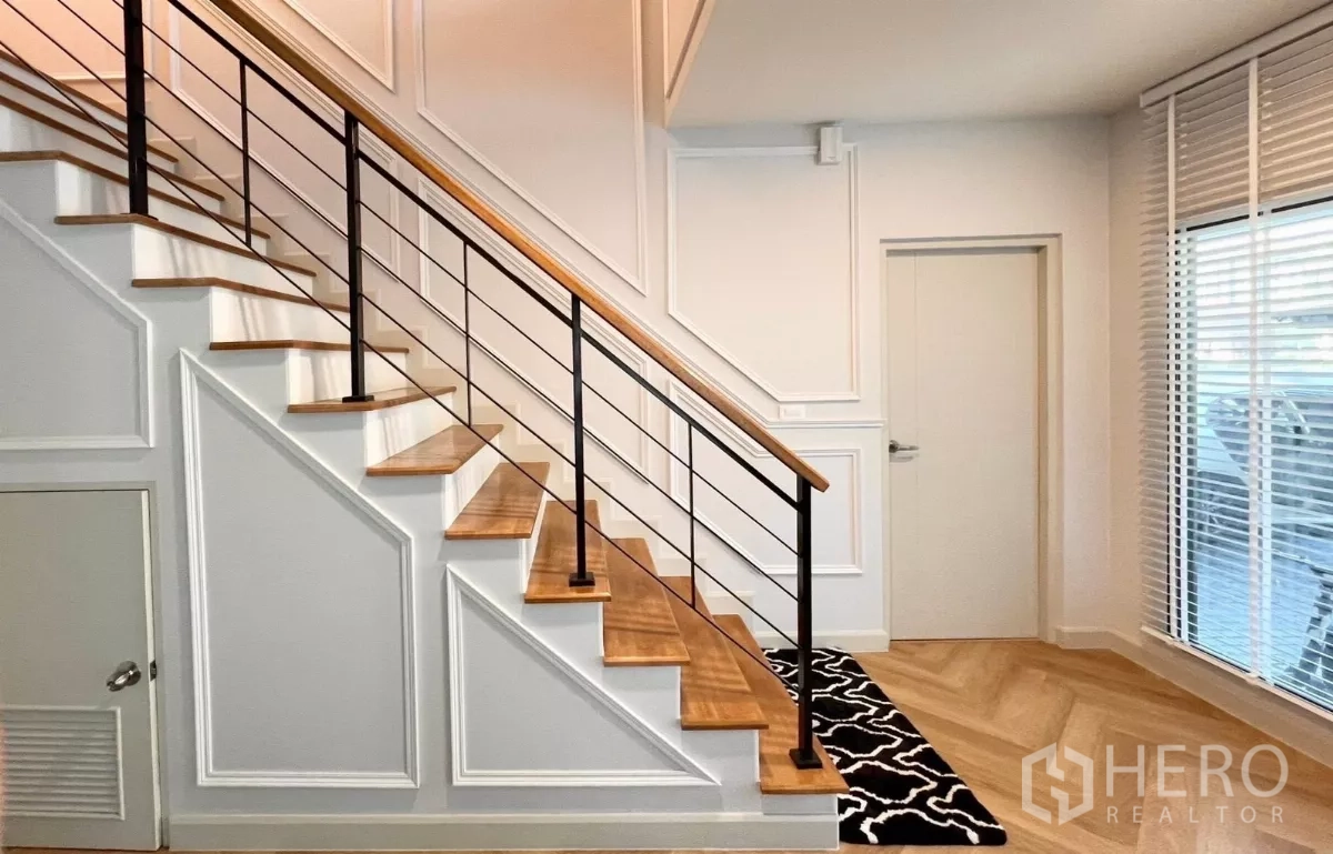 Detached House for rent in Bang Phli, Samut Prakan - Wooden staircase with black metal railing and storage under the stairs.