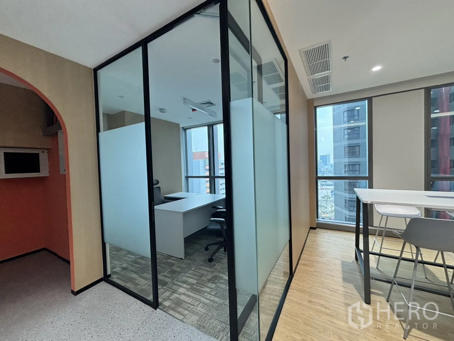 Office Space for rent in Huai Khwang, Bangkok - Glass-partitioned manager room beside a pantry-style collaboration bar table.