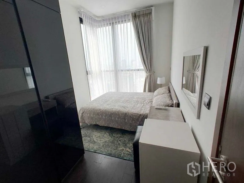 คอนโด ให้เช่าในWatthana, Bangkok - ห้องนอนอบอุ่นพร้อมเตียง โต๊ะหัวเตียง และผ้าม่านโปร่งเห็นวิวเมือง