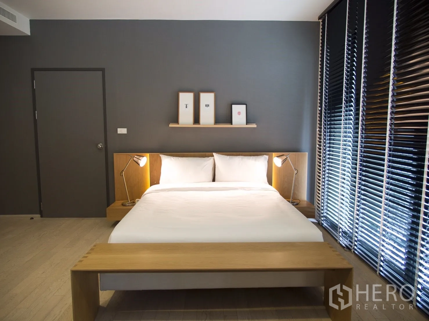 คอนโด ให้เช่าในWatthana, Bangkok - ห้องนอนใหญ่ เตียงคิงไซส์ ผนังสีเทาเข้ม ม้านั่งไม้ และมู่ลี่บานใหญ่