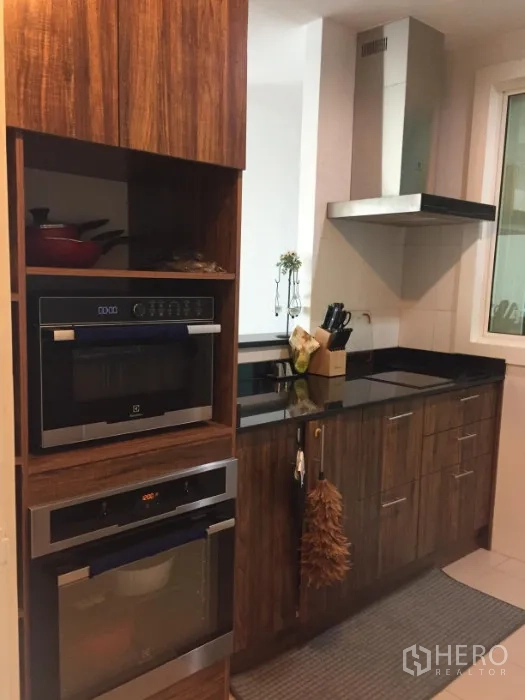 公寓 出租或出售在Khlong Toei, Bangkok - 现代厨房，木质橱柜、黑色花岗岩台面、内置烤箱与抽油烟机。