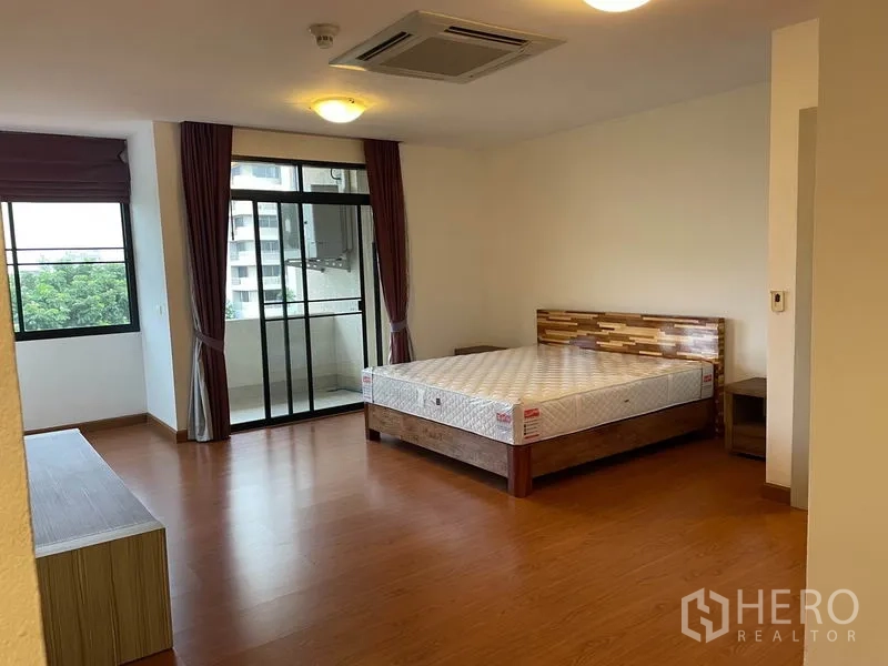 公寓 出租在Watthana, Bangkok - 主卧空间宽敞，玻璃门通阳台，木地板。