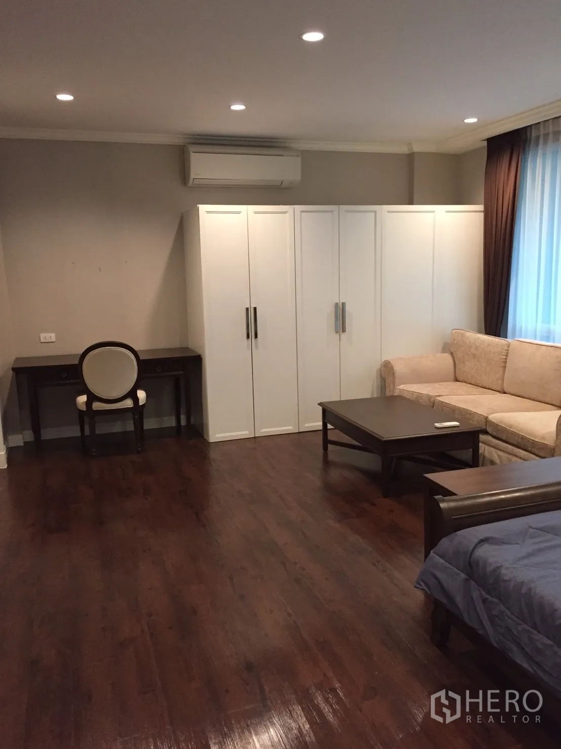 คอนโด ขายในHuai Khwang, Bangkok - ห้องนอนกว้าง ปูพื้นไม้เงา มีตู้เสื้อผ้า โซฟา และโต๊ะทำงาน