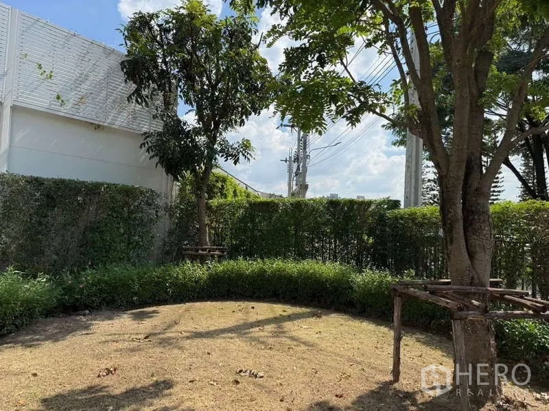 Detached House for rent or sale in Bang Bua Thong, Nonthaburi - Shaded backyard area with mature trees, trimmed hedges, and open lawn.