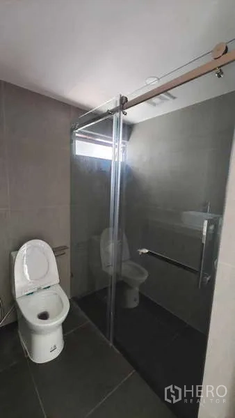 คอนโด ขาย - ห้องน้ำกระเบื้องสีเข้ม พร้อมตู้กระจกกั้นอาบน้ำและโถสุขภัณฑ์