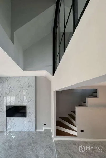 联排别墅 出租或出售在Prawet, Bangkok - 客厅视角，可见大理石电视墙与楼梯空间