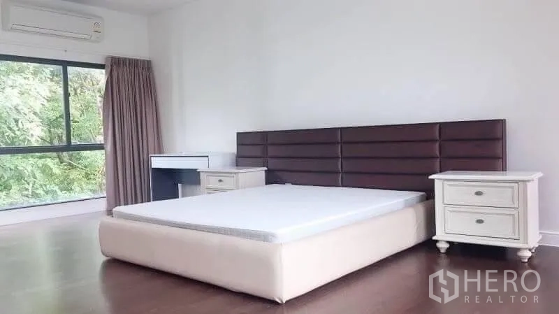 Detached House for rent in Bang Kapi, Bangkok - Spacious master bedroom with large windows, wood flooring and an upholstered headboard.