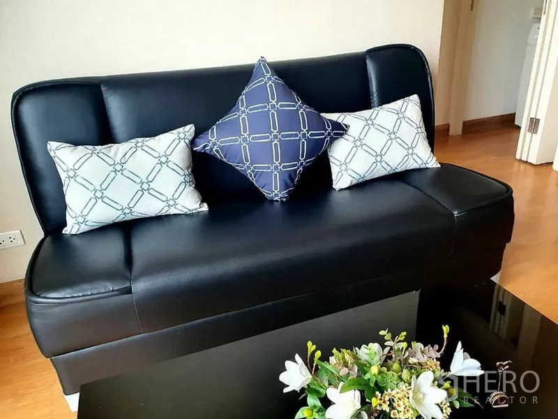 คอนโด ให้เช่าในWatthana, Bangkok - ห้องนั่งเล่นโซฟาหนังสีดำ หมอนอิงลายกราฟิก และโต๊ะกลางหน้าแก้ว