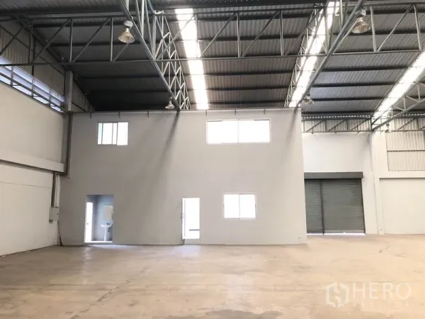 工厂 出租在Pathum Thani - 室内视角：两层办公室盒体、宽大卷闸门与开阔生产区。