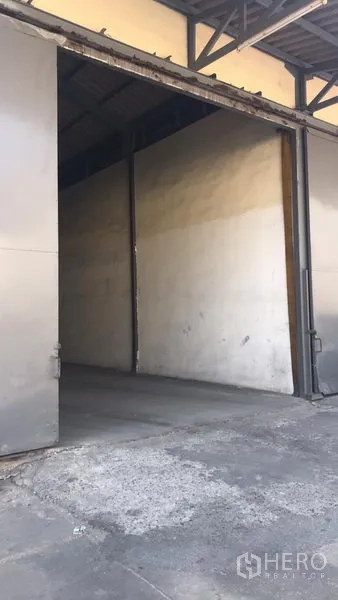 Factory for rent in Bang Pakong, Chachoengsao - Wide sliding metal door and covered loading bay opening into a high-ceiling warehouse.