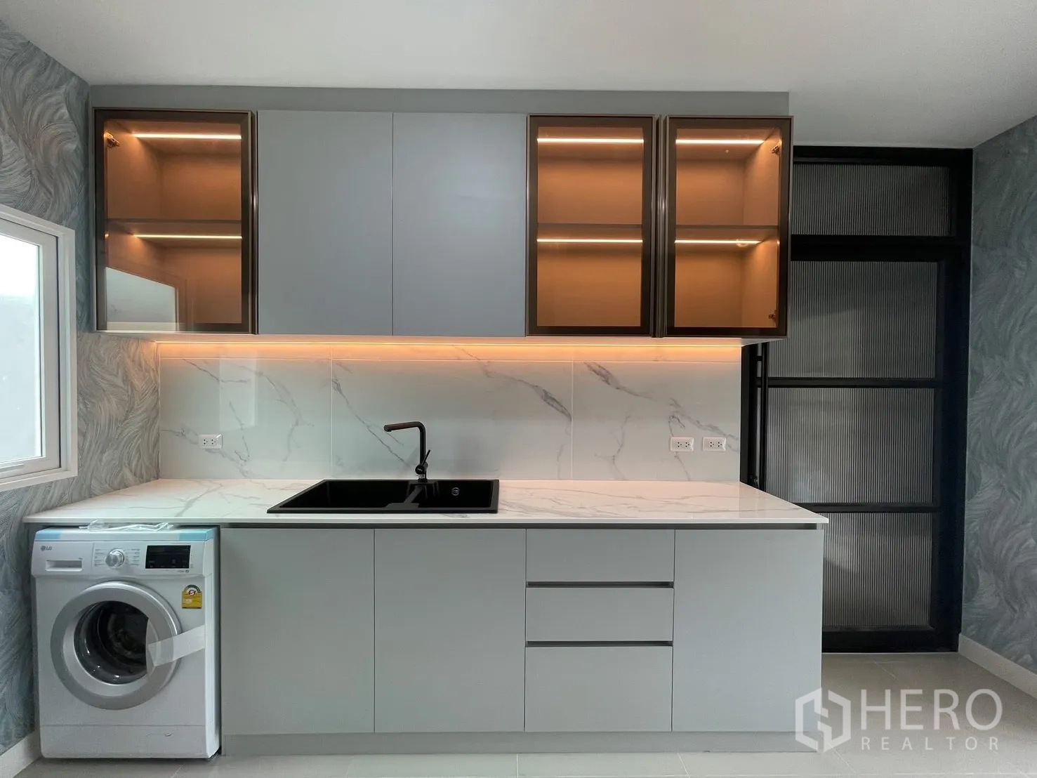 Semi-detached House for rent in Bang Phli, Samut Prakan - Modern pantry kitchen with marble backsplash, lit glass cabinets, black sink and a front-load washer.