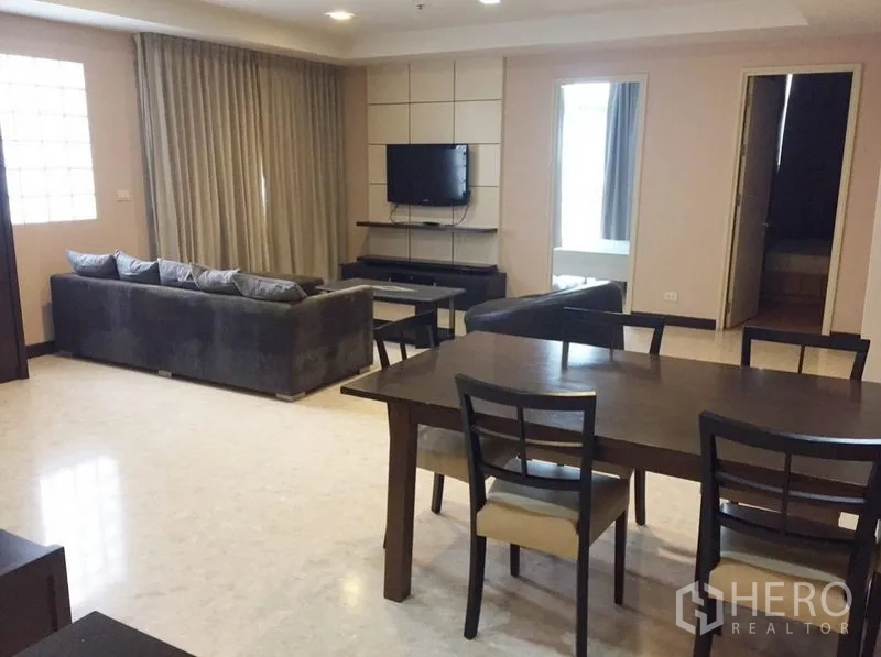 คอนโด ให้เช่าในKhlong Toei, Bangkok - พื้นที่นั่งเล่นและรับประทานอาหารแบบเปิดโล่ง มีทีวี โซฟา และผ้าม่านยาวเต็มผนัง