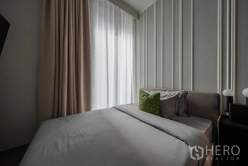 Condominium for rent - Second bedroom with textured wall panels, sheer curtains and soft bedding.