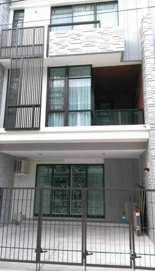 Townhouse for rent in Bang Phli, Samut Prakan - Modern three-storey townhouse facade with gated carport, large windows and balcony.