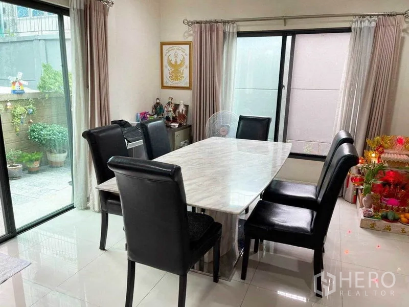 บ้าน ขายในPrawet, Bangkok - ห้องทานอาหาร โต๊ะหินอ่อน เก้าอี้หนังหกที่นั่ง และประตูบานเลื่อนออกสู่เฉลียง