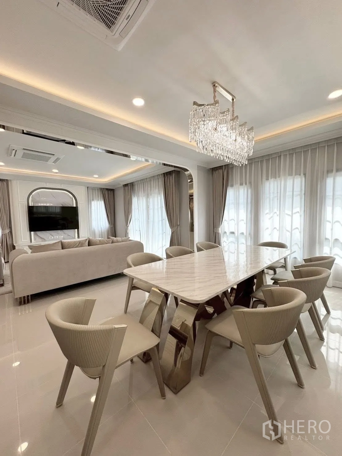 Detached House for rent in Bang Phli, Samut Prakan - Dining area with marble table, eight chairs and crystal chandelier beside the living room.
