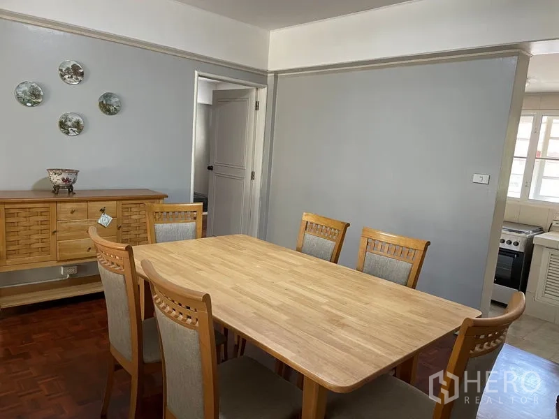 公寓 出租在Watthana, Bangkok - 餐区设六人木质餐桌，紧邻厨房。