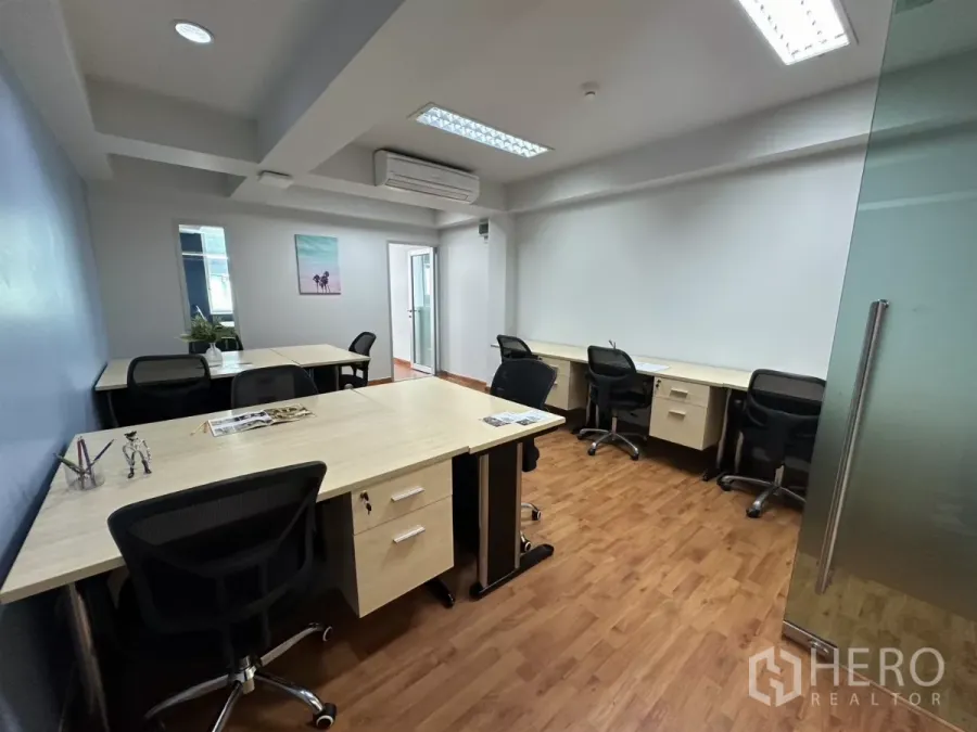 Office Space for rent in Watthana, Bangkok - Open-plan furnished office with multiple desks, mesh chairs, wood floors and a glass entry.