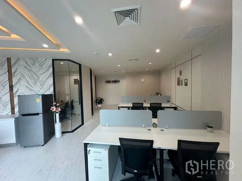 Office Space for rent - Multiple workstations with privacy screens next to glass meeting room and pantry.