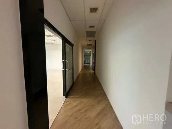 Office Space for rent in Ratchathewi, Bangkok - Long hallway with sliding glass door to a meeting room and wood-look flooring.