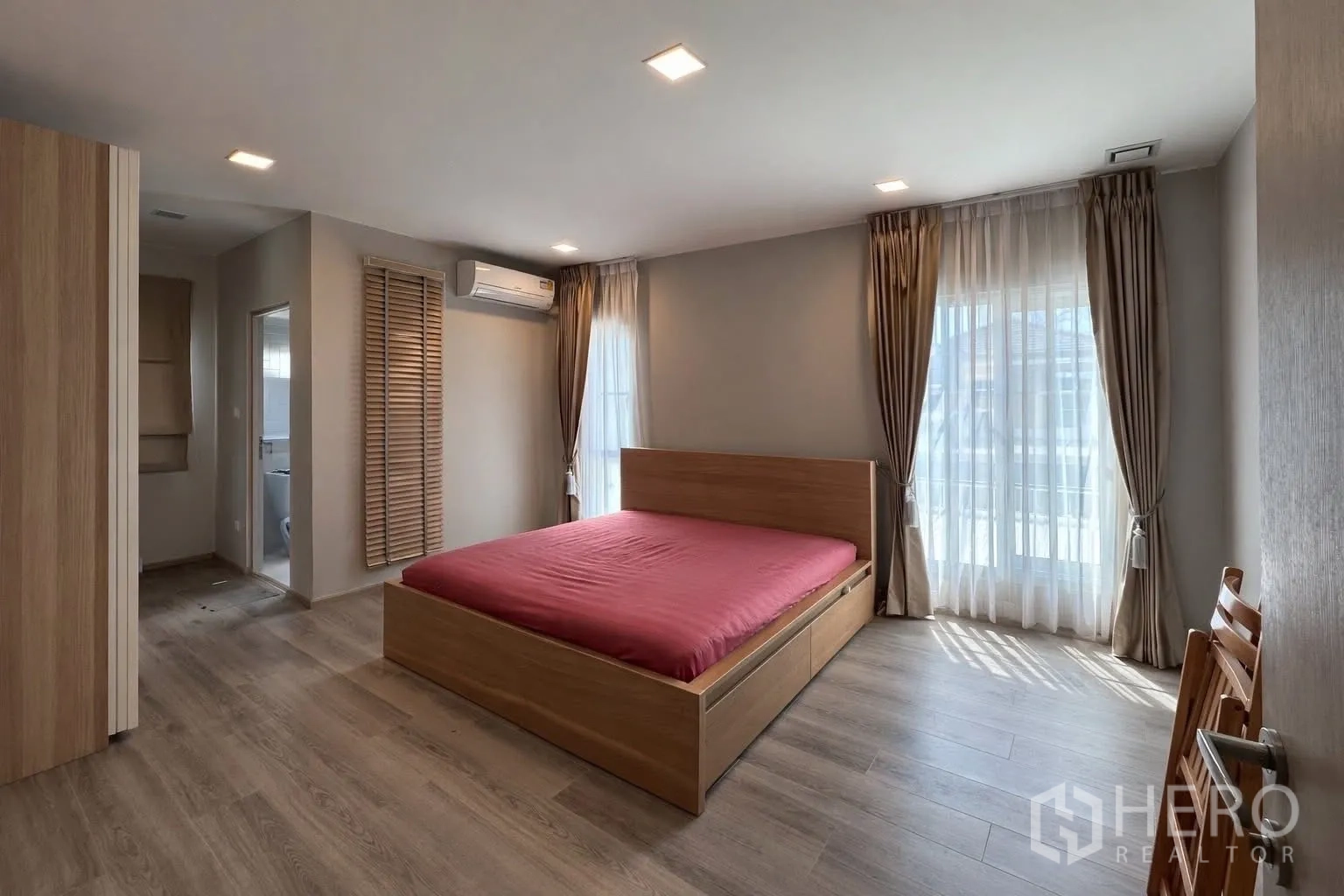บ้านแฝด for rent in Prawet, Bangkok - ห้องนอนใหญ่มีหน้าต่างบานกว้าง เตียงไม้ และทางเข้าห้องน้ำ