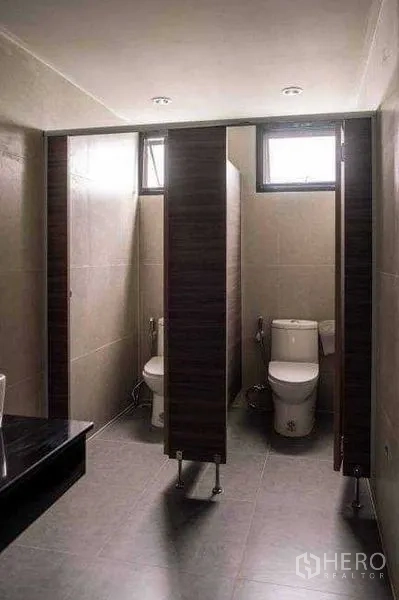 Office Space for rent or sale in Lak Si, Bangkok - Tiled restroom with private stalls, windows for ventilation, and modern fixtures.