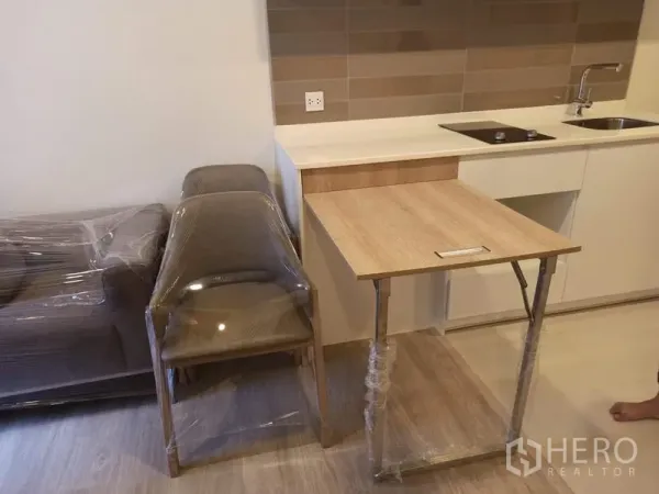 คอนโด ขายในDin Daeng, Bangkok - โต๊ะทานอาหารพับได้ข้างครัว พร้อมเก้าอี้และโซฟาที่ห่อพลาสติก