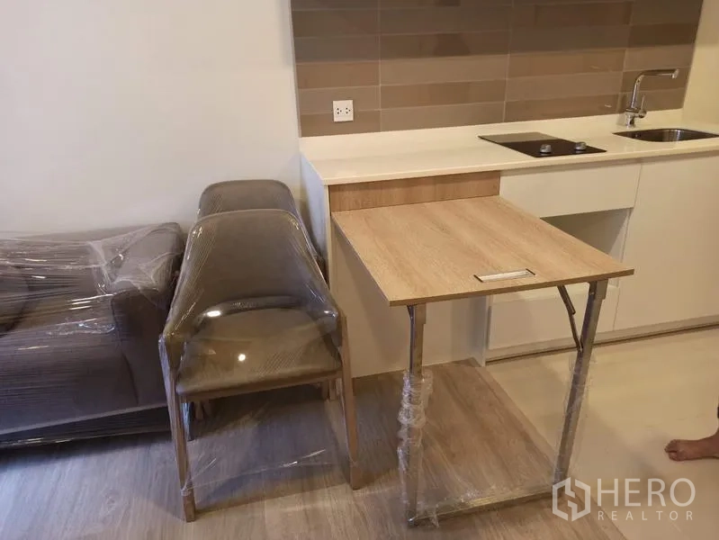 คอนโด ขายในDin Daeng, Bangkok - โต๊ะทานอาหารพับได้ข้างครัว พร้อมเก้าอี้และโซฟาที่ห่อพลาสติก