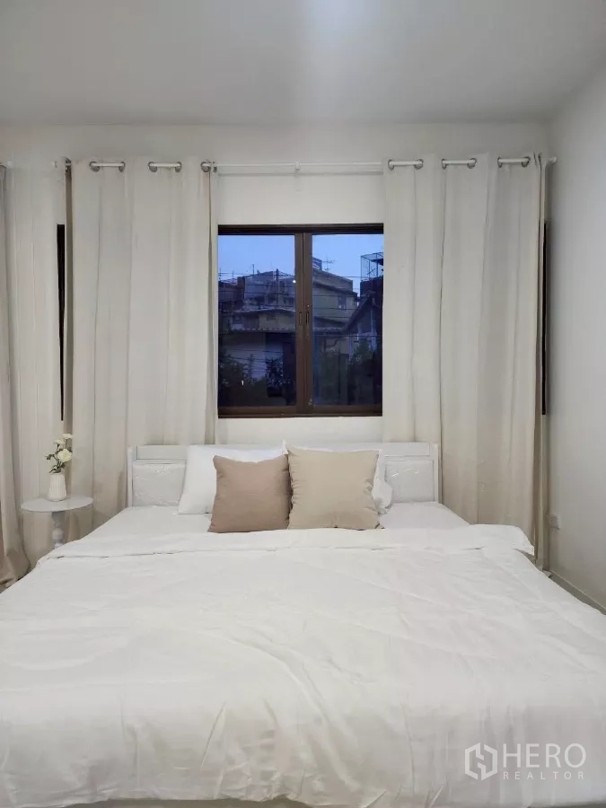 Detached House for rent in Chatuchak, Bangkok - Guest bedroom with king bed, neutral bedding and curtain-framed window.