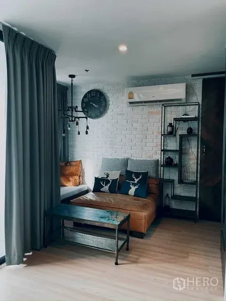 Condominium for rent in Suan Luang, Bangkok - Suan Luang condo living room with white brick wall, leather sofa, and industrial shelving