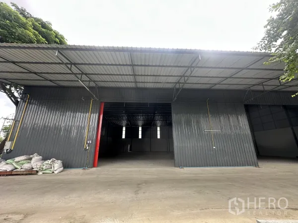 Warehouse for rent in Lam Luk Ka, Pathum Thani - New metal-clad warehouse exterior with wide roller door openings and a large concrete loading yard.