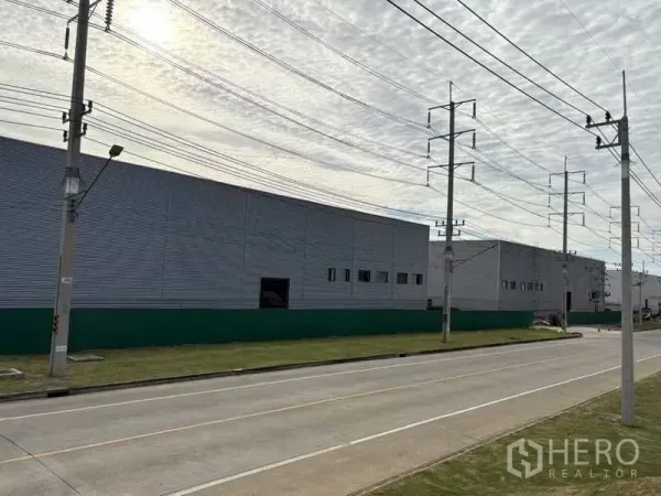 工厂 出租在Rayong - 罗勇Pluak Daeng沿宽阔道路的金属外墙工厂外观，设有电力线。