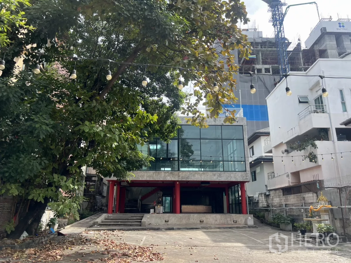 独立商业地产 出租在Din Daeng, Bangkok - 多层玻璃外立面正面视角，前场开阔并有串灯。