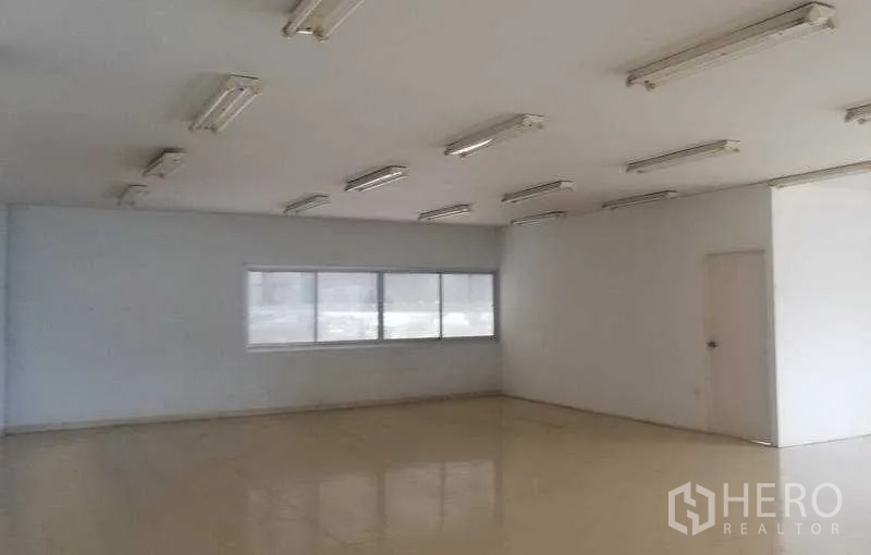 Warehouse for rent in Bang Phli, Samut Prakan - Bright office space with fluorescent lighting, tiled floors, and windows overlooking the yard.