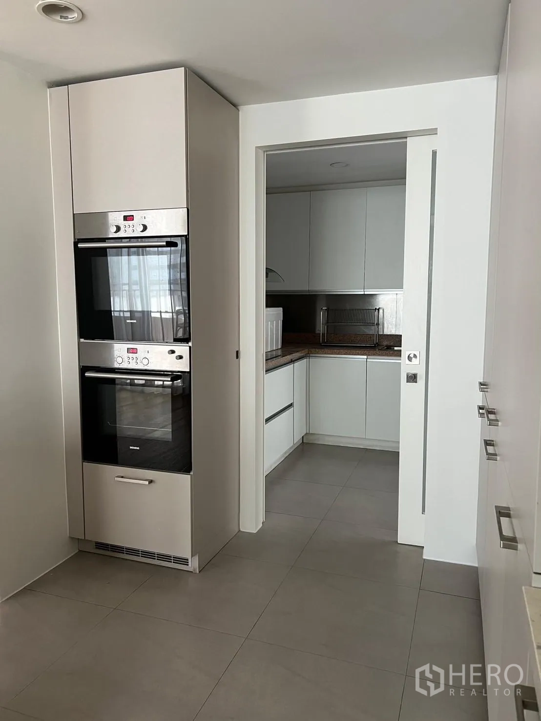 คอนโด ให้เช่าหรือขายในSathon, Bangkok - ครัวสมัยใหม่ เตาอบบิวท์อินคู่ และประตูเลื่อนไปยังห้องเตรียมอาหาร