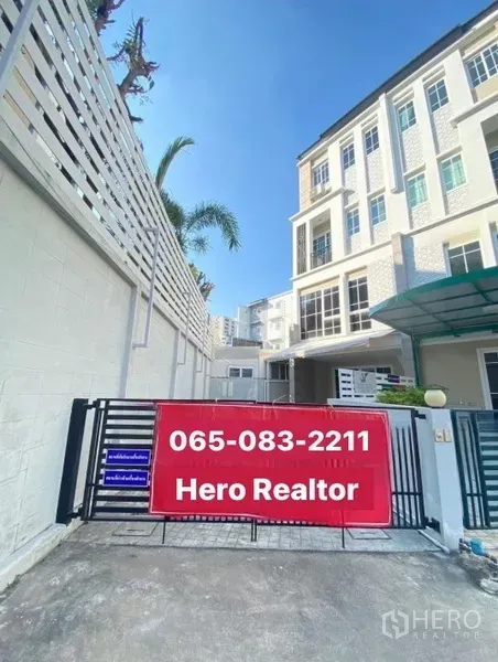 带办公室的家 出租或出售 - 四层家庭办公房的社区大门与红色招牌，前方为车道入口。