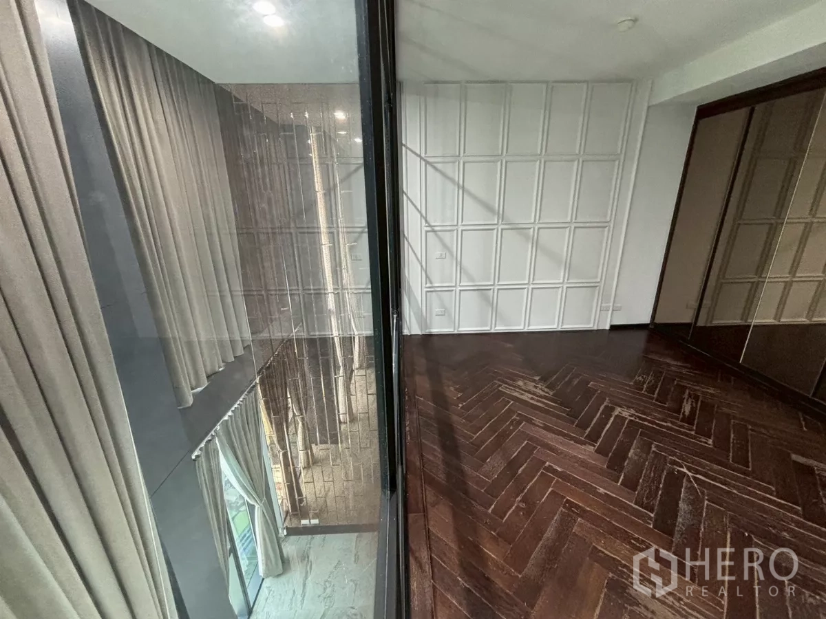 Condominium for sale in Bang Kho Laem, Bangkok - View through glass partition to double-height area with drapes and city scenery below.