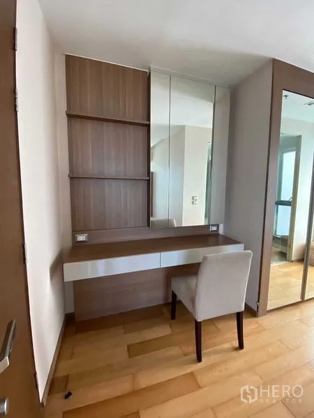 Condominium for sale in Ratchathewi, Bangkok - Built-in dressing table with mirror, shelves and chair next to a wardrobe.