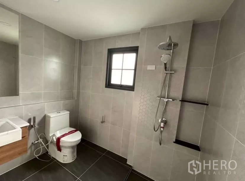独立式住宅 出租在Bang Phli, Samut Prakan - 现代化浴室，步入式淋浴、坐便器、灰色瓷砖与窗户。