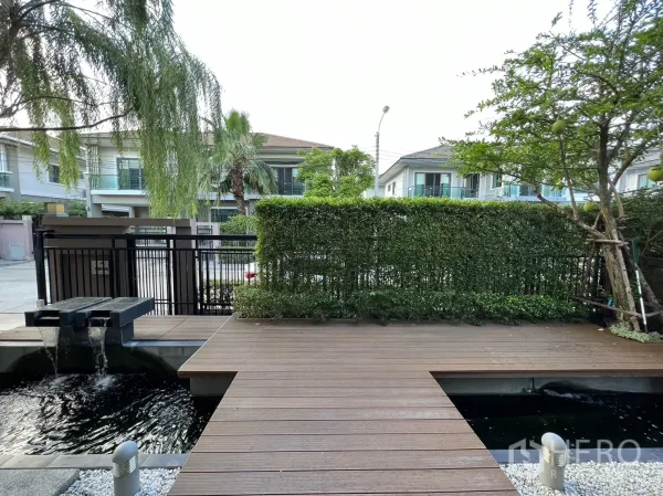 Detached House for rent in Suan Luang, Bangkok - Front yard deck with decorative water feature and street view beyond hedge fence.