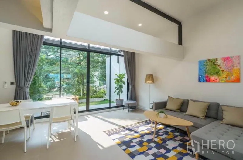 ทาวน์เฮาส์ ให้เช่าในKhlong Toei, Bangkok - ห้องนั่งเล่นเพดานสูง ผนังกระจกเต็มบาน โซฟาตัวแอลสีเทา