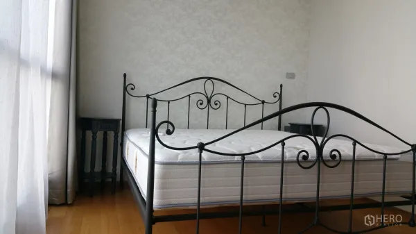 คอนโด ให้เช่าหรือขายในWatthana, Bangkok - ห้องนอนรับแสงด้วยเตียงเหล็กดัดสีดำ โต๊ะข้างเตียง และม่านโปร่ง