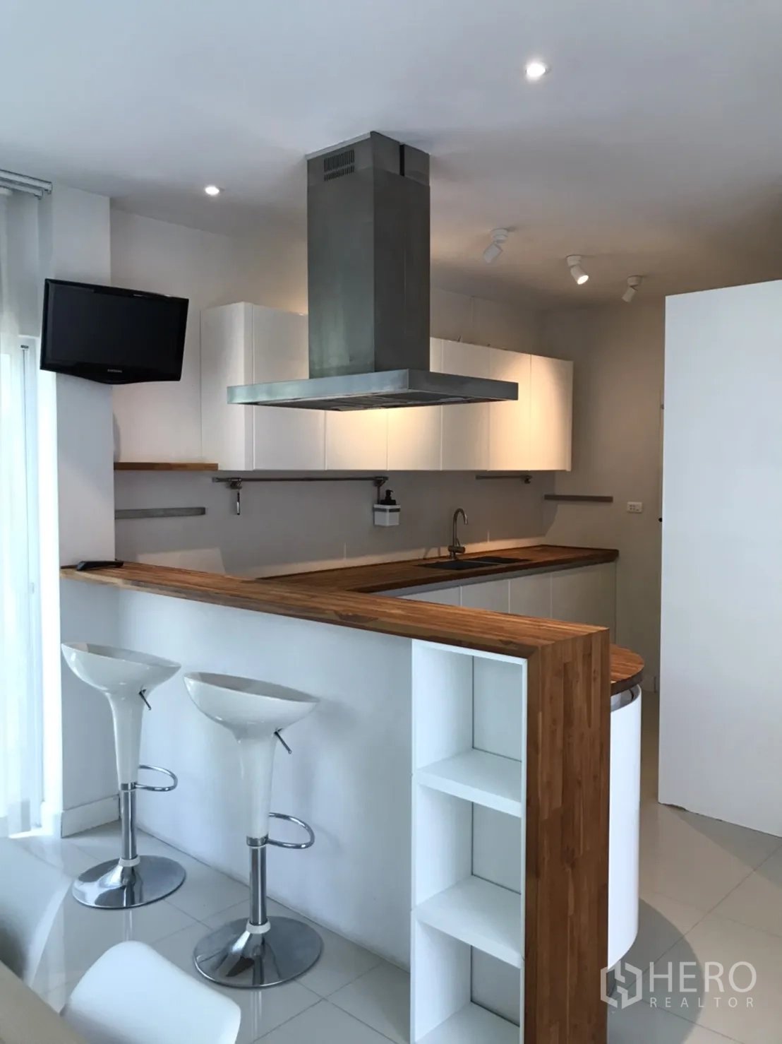 独立式住宅 出租或出售在Saphan Sung, Bangkok - 现代厨房，吧台、中置抽油烟机与白色吧椅。