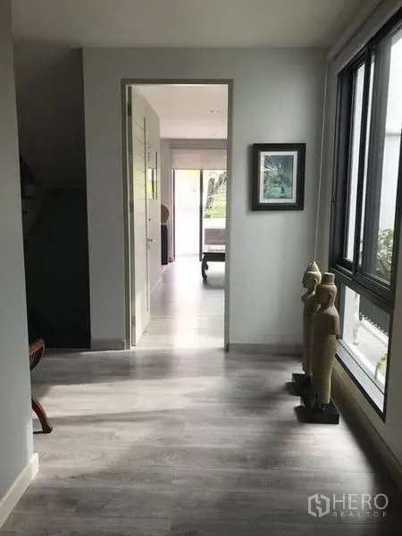 Townhouse for rent in Khlong Toei, Bangkok - Upstairs corridor with large window, grey flooring and decorative statues.