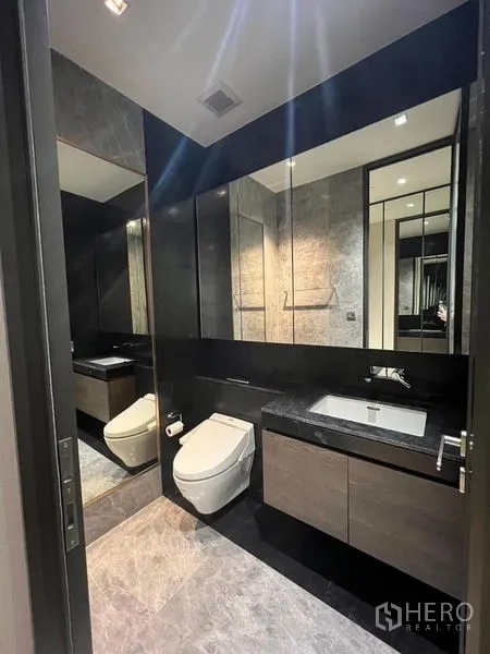 Condominium for rent - Bathroom with long stone countertop, wide mirror, and modern fixtures.
