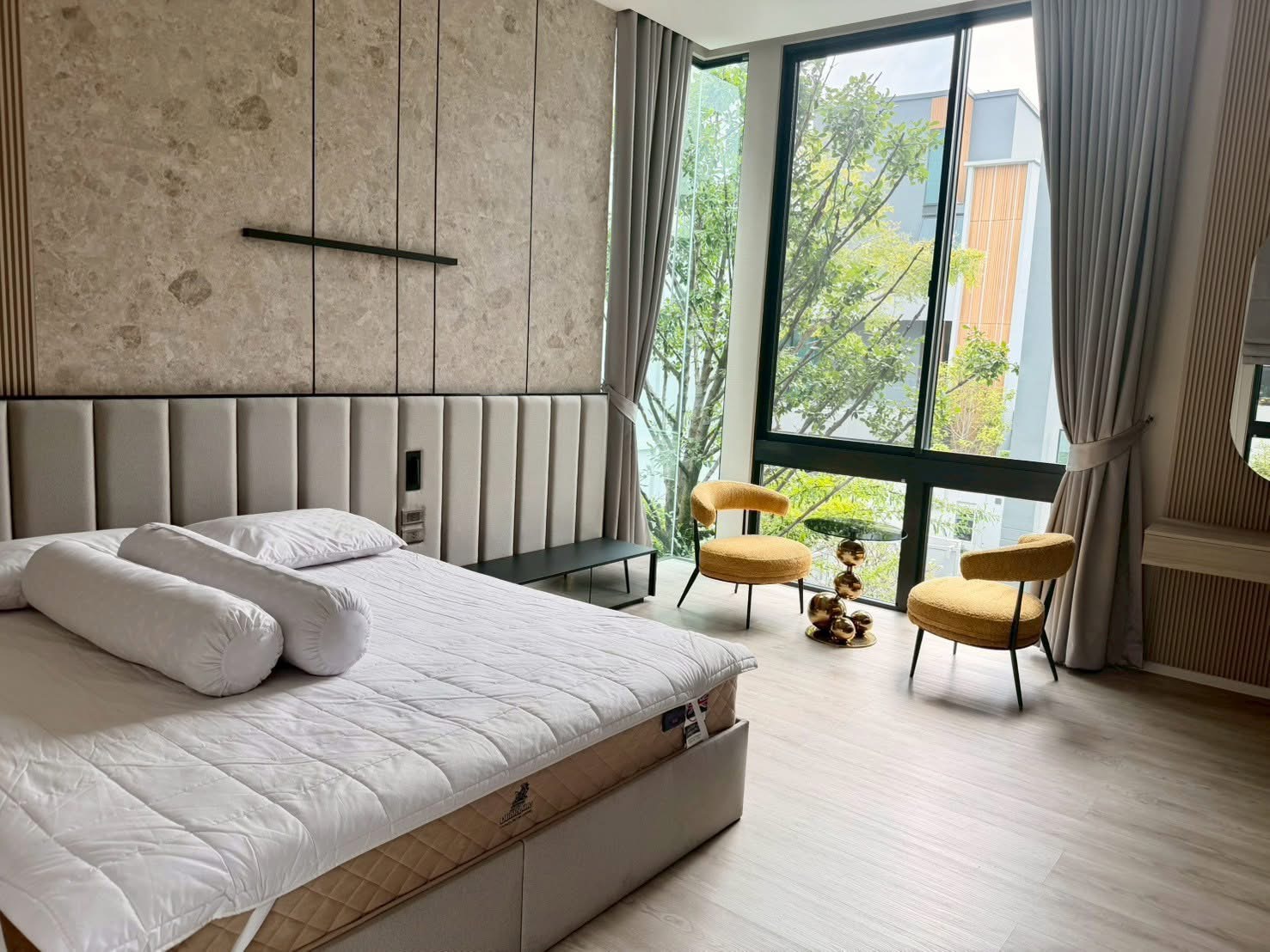 Detached House for rent in Saphan Sung, Bangkok - Bedroom with king bed, tall windows, and two mustard lounge chairs with side table.